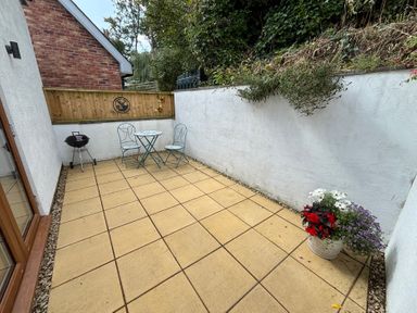 An outdoor patio with table and chairs at Honey Bee Cottage in Welshpool