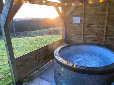 A hot tub in a wooden structure with a sunset view at Shepherds hut Dumfries