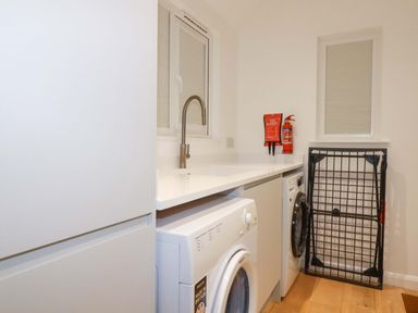 A laundry room with washing machine and tumble dryer at Poldreth in Truro