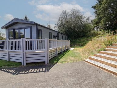 An outdoor view of a vacation home with a deck and steps at The Pines 3 Bedrooms, Delamere