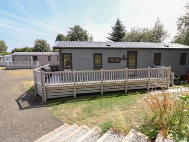 A mobile home with a deck and pathway at The Pines 3 Bedrooms Delamere