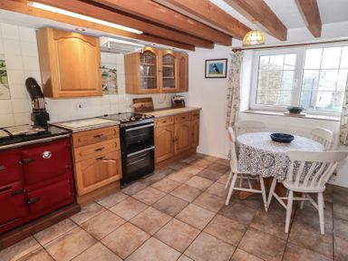 A kitchen with cabinets and a table at Rhosgranog Cottage Llandeloy near Solva