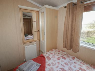 A bedroom with a bed and storage cabinet at Rhosgranog Caravan Llandeloy near Solva