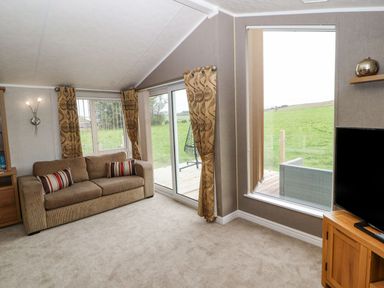 A living room with a sofa and television at No 8 Hillcote Lodge in Cockermouth