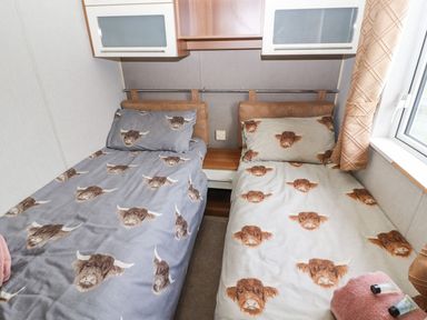 A bedroom with twin beds and a shelf at No 8 Hillcote Lodge in Cockermouth