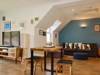 A living room with a sofa and television at Lowenna Watergate Bay near Newquay