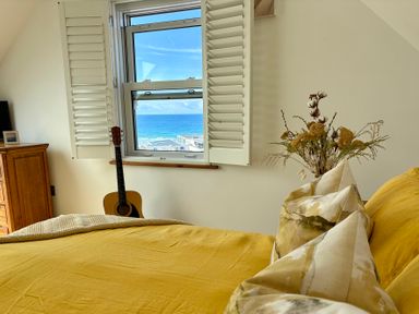 A bedroom with a bed and window overlooking the ocean at Lowenna Watergate Bay near Newquay