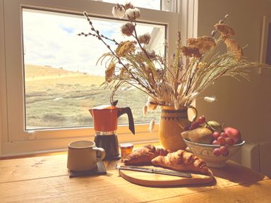 A kitchen with coffee, croissants and a fruit bowl at Lowenna, Watergate Bay near Newquay