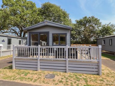 A house with a deck and fence at The Oaks 2 Bedrooms Delamere