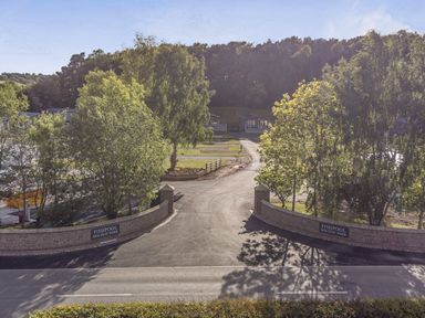 An outdoor view of Fishpool Holiday Park with trees and a road in Delamere