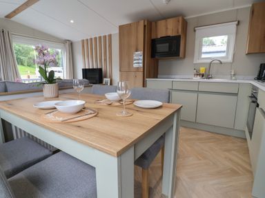 A kitchen with a dining area featuring a table and chairs at The Oaks 2 Bedrooms Delamere