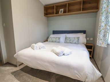 A bedroom with a bed and shelves at The Oaks 2 Bedrooms in Delamere