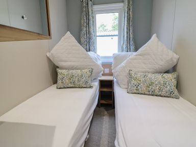 A bedroom with two beds and a window at The Oaks 2 Bedrooms in Delamere
