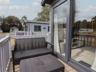 An outdoor seating area with a table and chair at The Oaks 2 Bedrooms in Delamere
