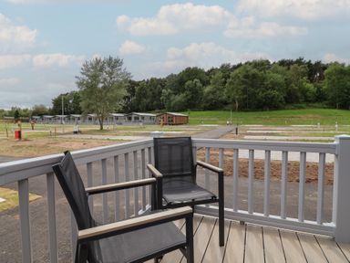 A deck with chairs overlooking a landscape at The Oaks 2 Bedrooms in Delamere