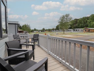 An outdoor balcony with chairs overlooking caravans at The Oaks 2 Bedrooms Delamere
