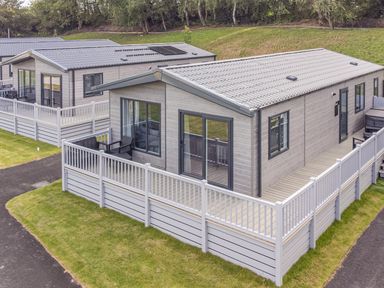 A holiday home with a deck and fence at Cedar Lodge 2 Bedrooms with hot tub Delamere