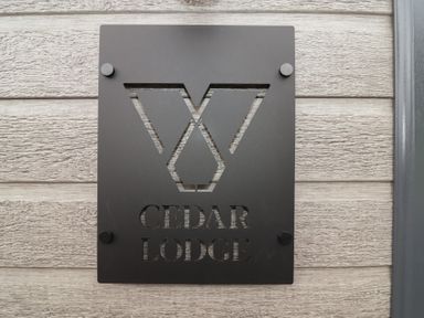 A sign displaying the name Cedar Lodge on a wooden wall