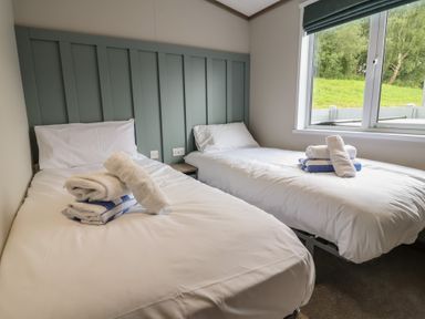 A bedroom with two single beds and towels at Cedar Lodge 2 Bedrooms with hot tub Delamere