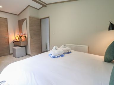 A bedroom with a bed and towels at Cedar Lodge 2 Bedrooms with hot tub Delamere