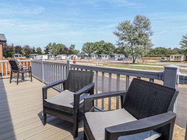 A deck with chairs overlooking caravans at Cedar Lodge 2 Bedrooms with hot tub in Delamere