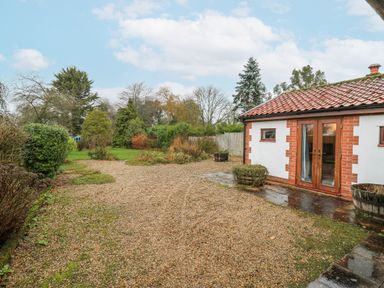 A garden with a gravel path and trees at The Pantiles in Banham