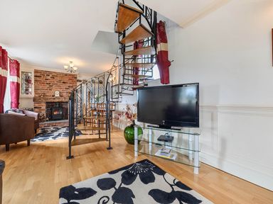 A living room with a staircase and television at Bank House Cottage in Glasson Dock