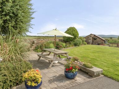 A garden with a table and umbrella at Bank House Cottage in Glasson Dock