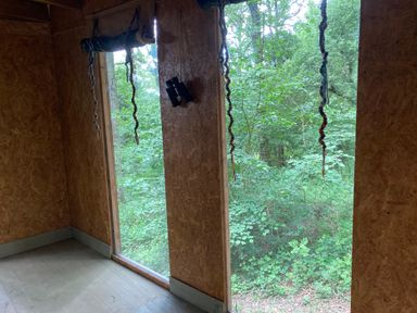 A room with windows overlooking trees at The Tree House in the Woods Longhope