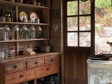 A kitchen with a wooden cabinet and mugs on a shelf at The Tree House in the Woods Longhope