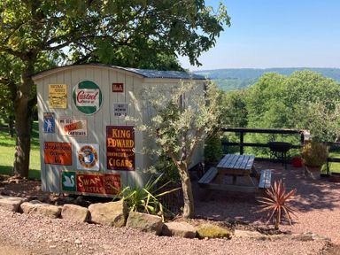 A garden area with a shed and picnic table at Cosy Shepherd’s Hut Longhope