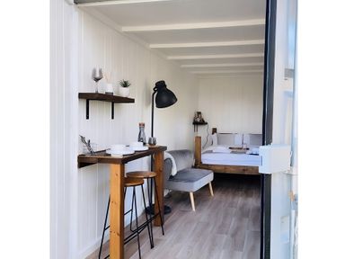 A interior view with a bed, sofa, and table at Trethowels Hidden Huts in St. Austell