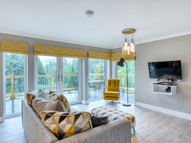 A living room with a sofa and television at Pinemarten Lodge Crianlarich
