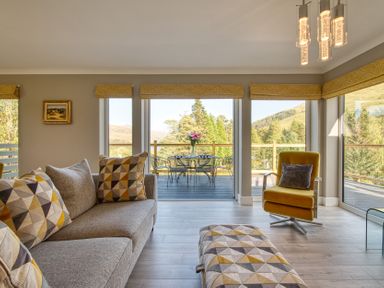 A living room with a sofa and a table at Pinemarten Lodge in Crianlarich