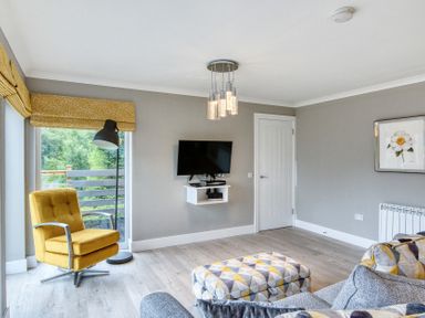 A living room with a television and seating at Pinemarten Lodge Crianlarich