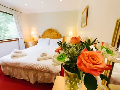 A bedroom with a bed and flowers at Buzzard Lodge in Crianlarich