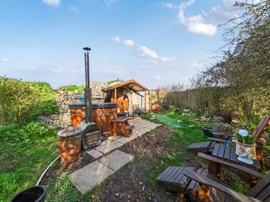 A garden with a wooden hot tub and seating area at Cosy Escape in Minster On Sea