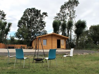 An outdoor area with a wooden cabin and chairs at Cotswold Nights Away Evesham
