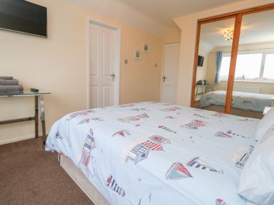 A bedroom with a bed and mirror at Tudor Rose in Weymouth