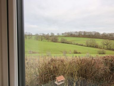 A view of a green field with trees and hills at 5 Hillview Lodges Cleobury Mortimer