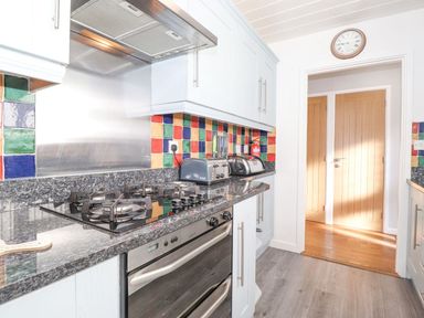 A kitchen with gas stove and colorful tiles at Wansfell View in Ambleside