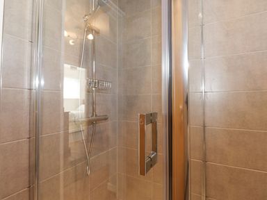 A shower with chrome fittings and tiled walls at Wansfell View in Ambleside