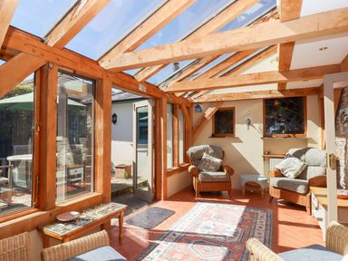 A conservatory with wooden beams and chairs at Pillars in Barnstaple