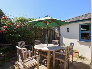 A garden with a table and chairs under an umbrella at Pillars Barnstaple