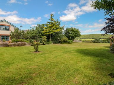 A garden with lush grass and trees at Pillars in Barnstaple