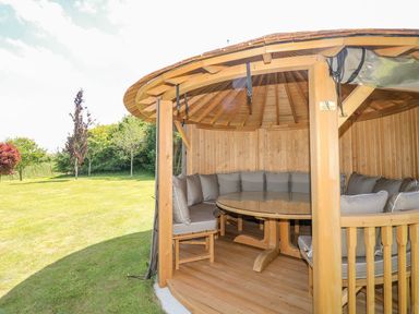 A gazebo with a round table and cushioned seating in the garden at Pillars, Barnstaple