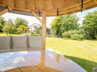 A gazebo with cushions and a table in the garden at Pillars Barnstaple