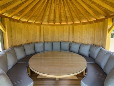 An outdoor seating area with a round table and cushioned seating at Pillars Barnstaple