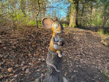 A wooden mouse sculpture in a forest setting at No 11 Old Pale View Sanctuary, Northwich