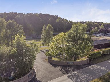 A view of a caravan park with trees and road at Fishpool Holiday Park in Delamere